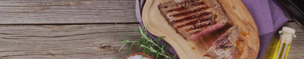 Grilled beef steak with rosemary, salt and pepper and red wine on wooden table. Top view